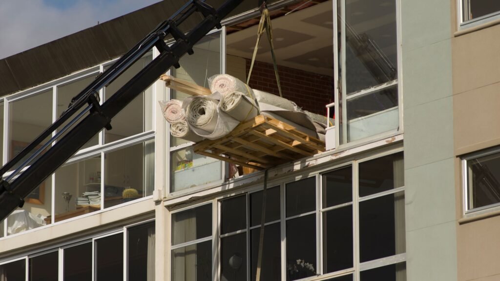 Içamento de móveis no centro de BH: tapetes sendo descidos de prédio com guindaste.