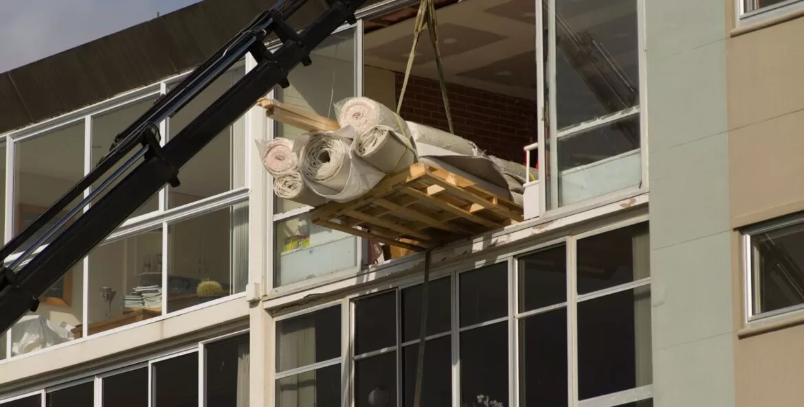 Içamento de móveis em Contagem: tapetes sendo descidos de prédio com guindaste.