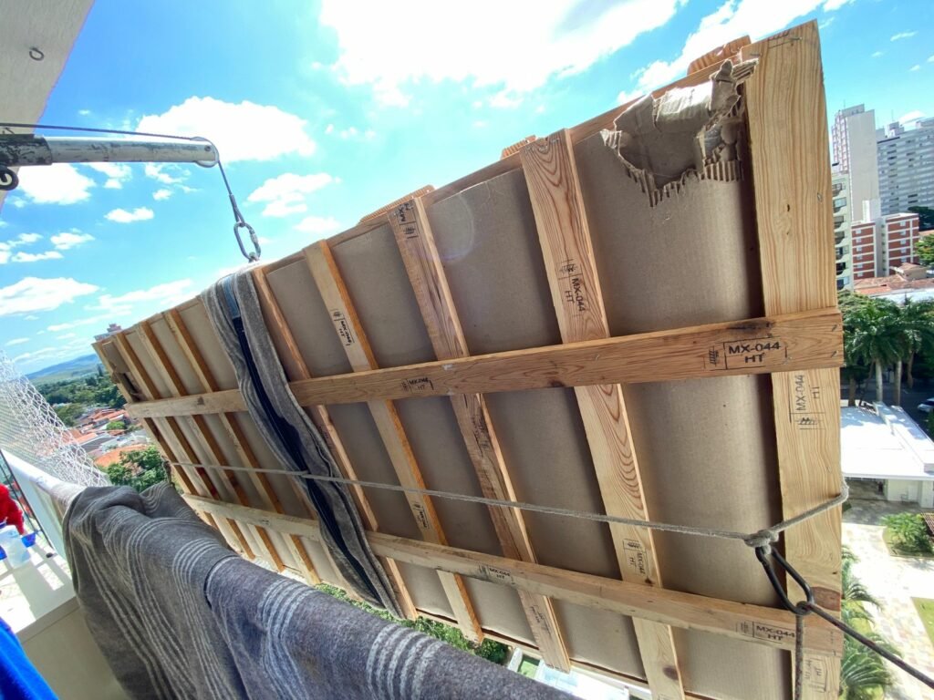 Içamento em nova lima: móvel sendo descido por uma varanda de um prédio alto com o auxilio de equipamento para içamento