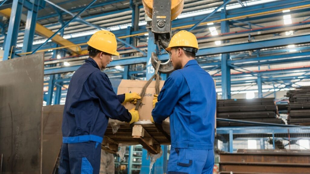 trabalhadores pendurando carga em guincho.