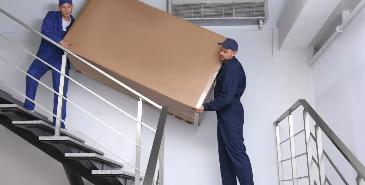 como subir geladeira em apartamento: dois homens carregando geladeira por escadas.