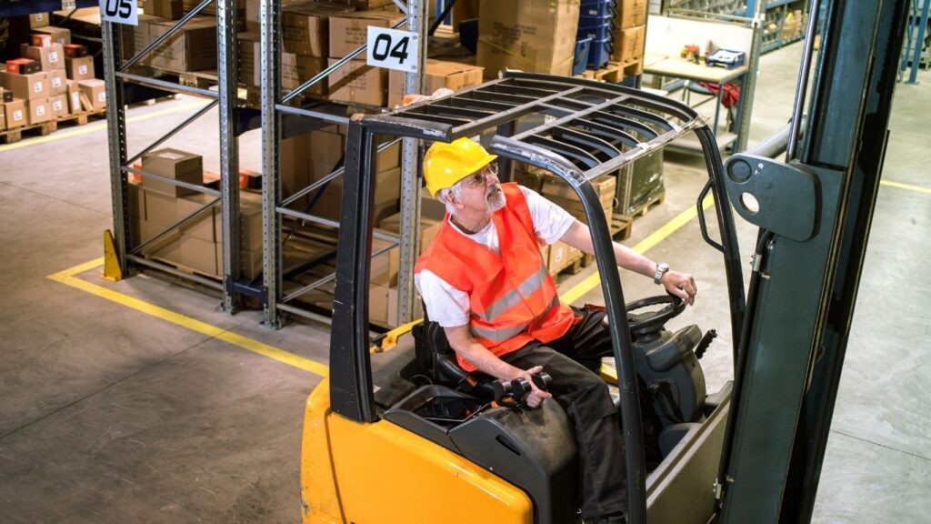trabalhador usando empilhadeira.