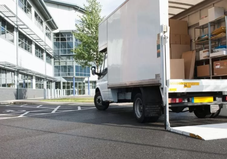 Mudanças nacionais: caminhão de mudança parado em frente a prédio com a caçamba aberta.