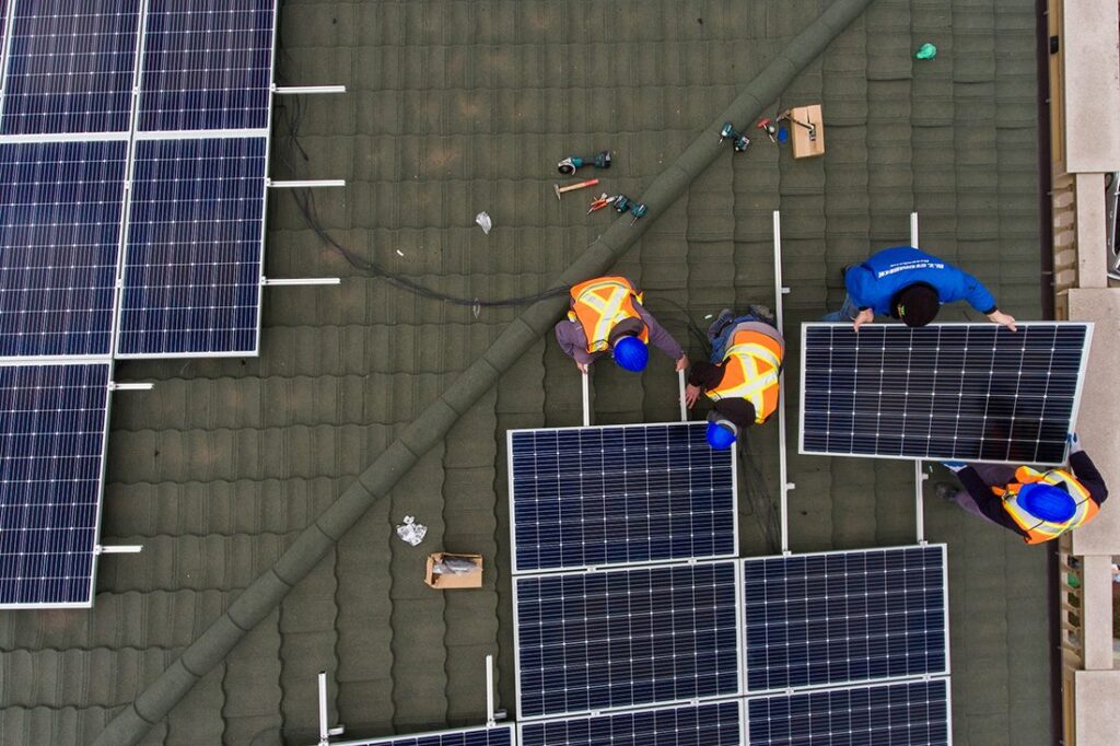 Içamento de placas solares: profissionais realizando instalação das placas em telhado