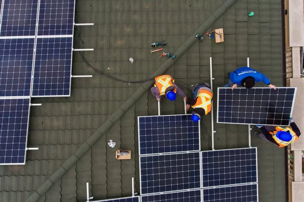 Içamento de placas solares: profissionais realizando instalação das placas em telhado