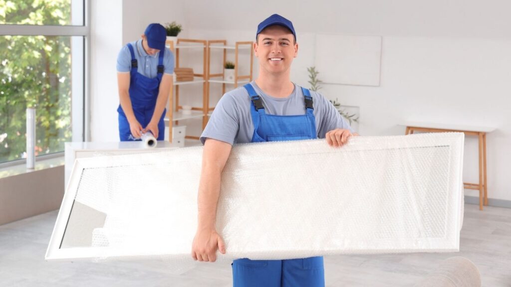 Como transportar espelho em mudanças: funcionário de empresa de mudança carregando espelho leve.